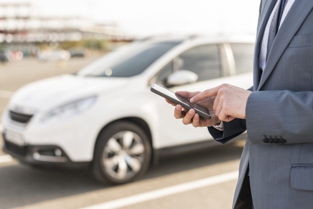 businessman-with-smartphone-in-front-of-car